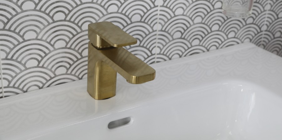gold tap against cream and grey tiles